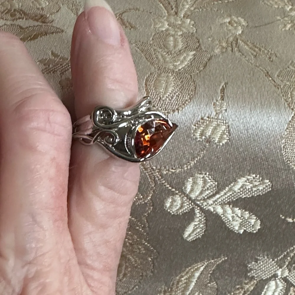 Ring in silver metal intricate with teardrop shaped amber color stone